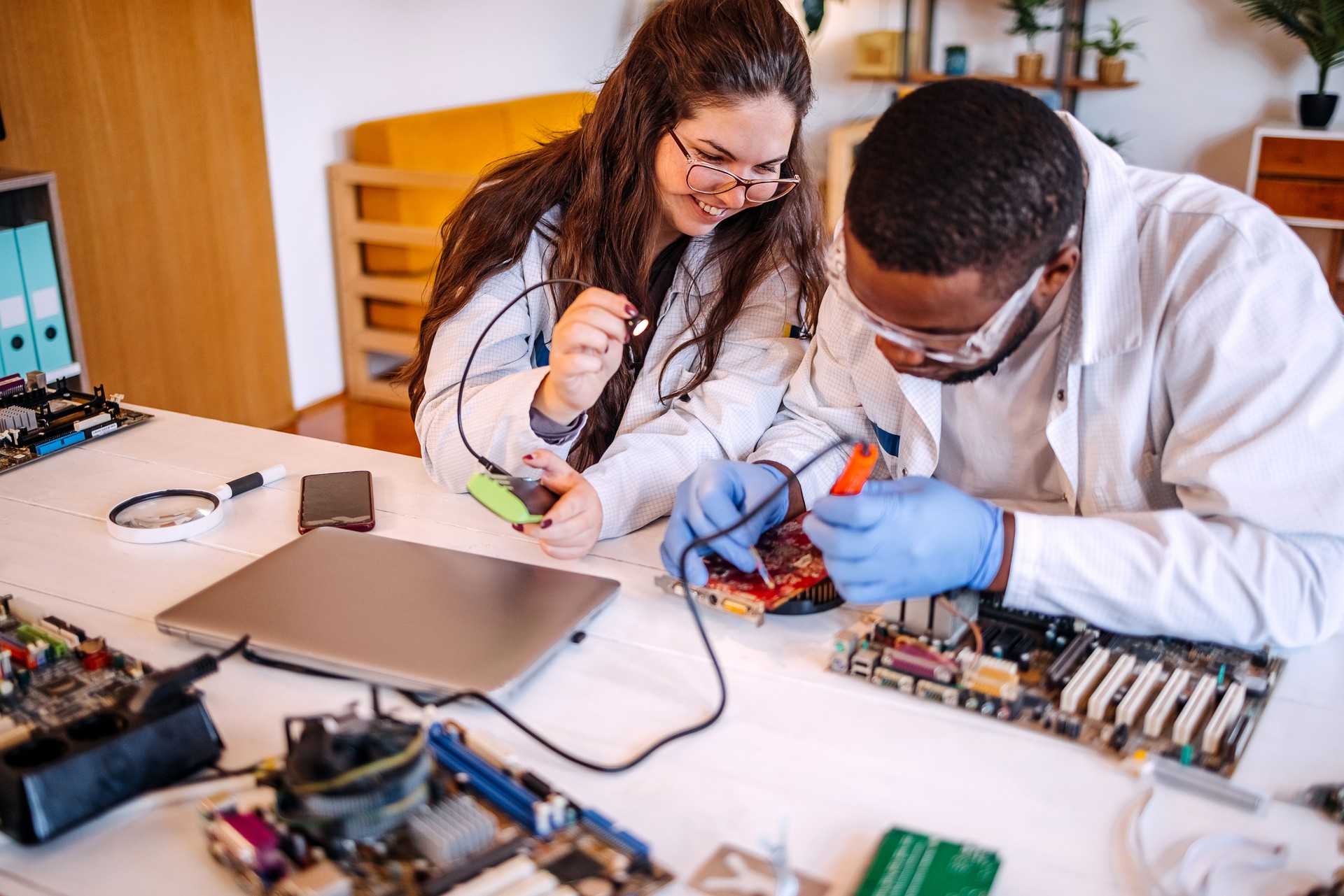 University students working together on project at home using electronic parts for computer build and supporting each other